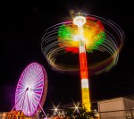 long exposure photograph of Ferris wheel and carnival swing at night